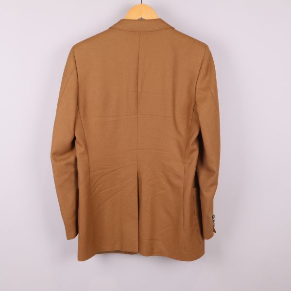 Baksida av beige kavaj med enkel slits