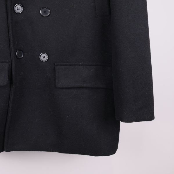 Närbild på knapp och ficka på svart kappa