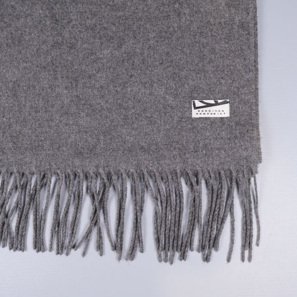 Närbild på grå halsduk med etikett och fransar