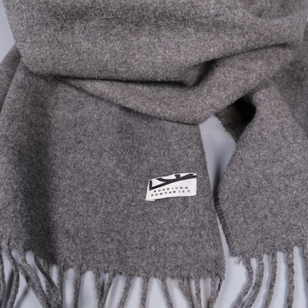 Detaljerad vy av etikett och fransar på grå halsduk