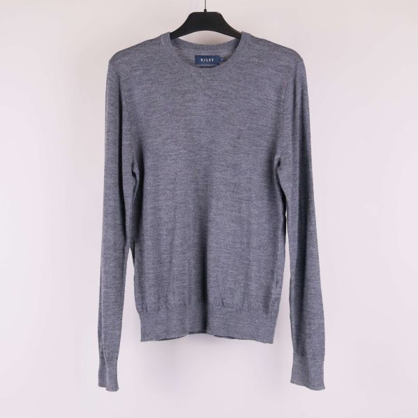 Stickad grå tröja med rund hals och långa ärmar hängande på galge