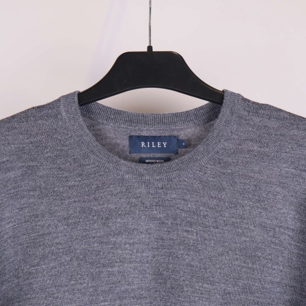 Närbild på halsringning av grå stickad tröja