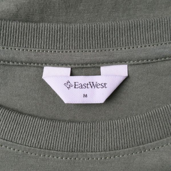 Närbild på etikett med EastWest och storleksmarkering M