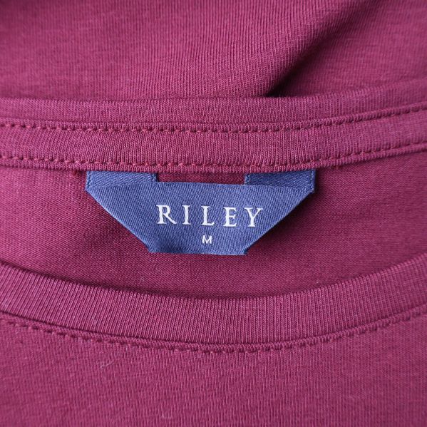 Närbild av Riley-logotyp på t-shirtens etikett