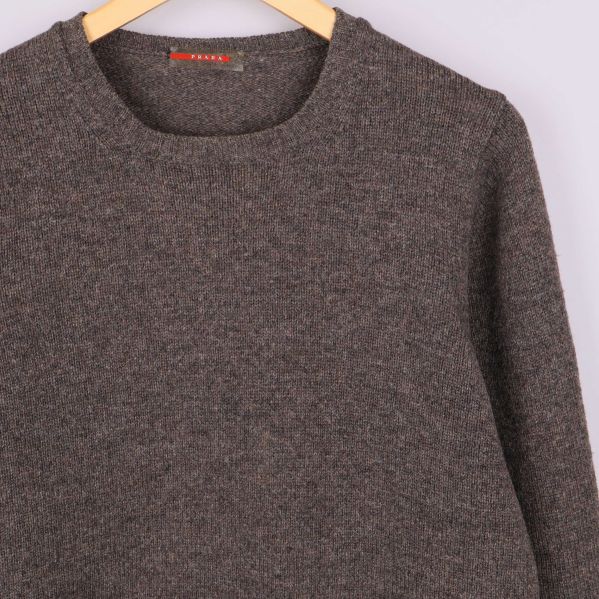 Överdel av brunmelerad stickad tröja samt axelparti