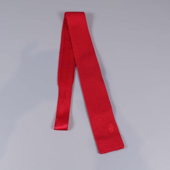 Röd stickad slips visad i hel längd mot grå bakgrund