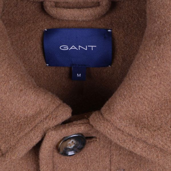 Närbild på mörkblå Gant-etikett i kragen på beige kavaj