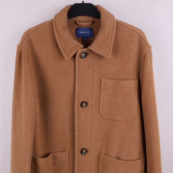 Närbild på övre delen av beige kavaj med utanpåficka och knappar