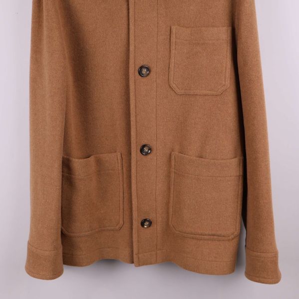 Nedre delen av kavaj visar två stora utanpåfickor och knappslå