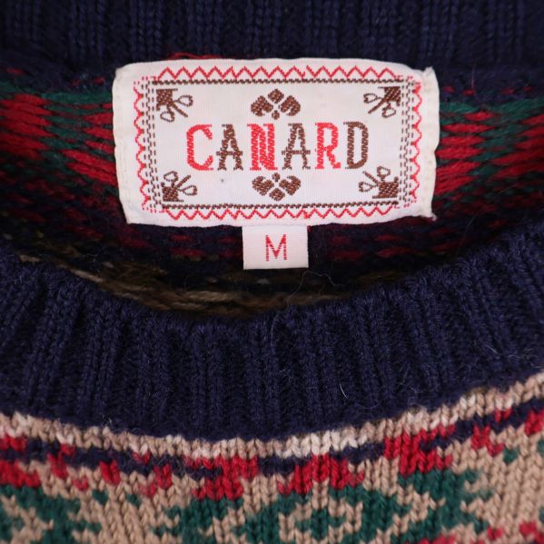Närbild på etikett märkt Canard och storlek M i tröjan