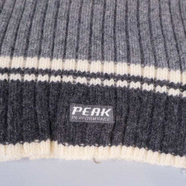 Närbild på Peak Performance logotyp och randdetalj på halsduk