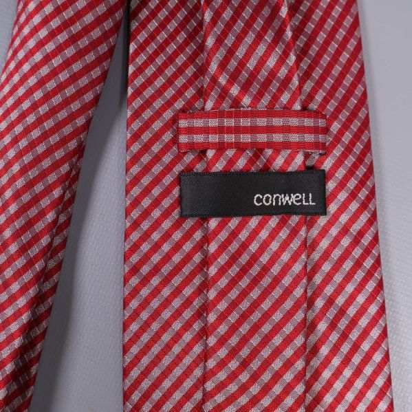 Närbild av etikett med texten Cornwell på rödvit slips