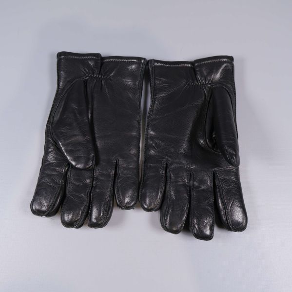 Baksidan av ett par svarta skinnhandskar med synliga sömmar