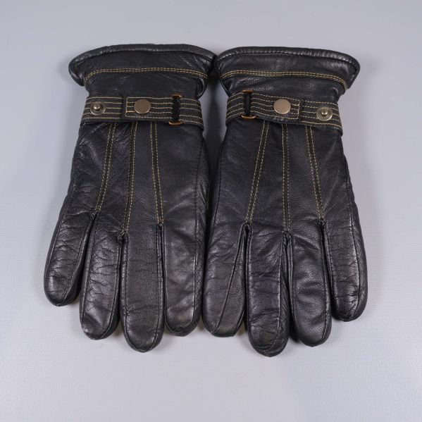 Handskar liggande med knappar och synliga guldsömmar ovanifrån