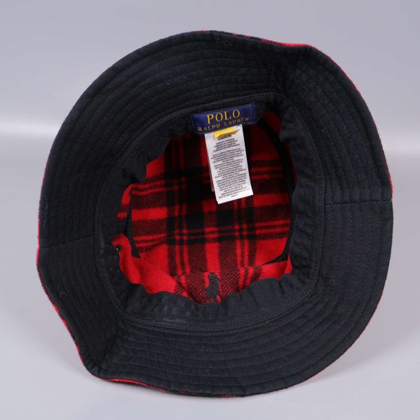 Insidan av bucket hat med svart kant och röd rutig fodring