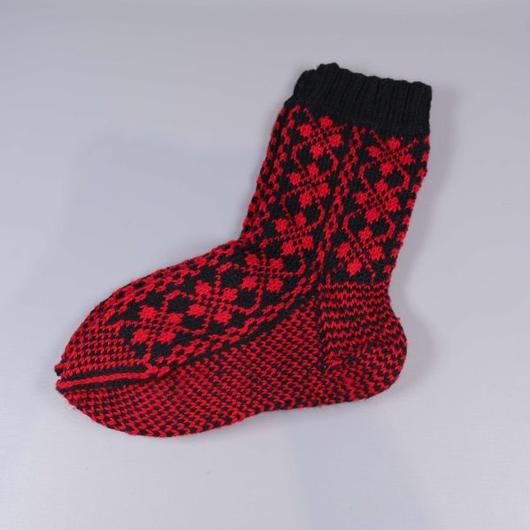 En stickad strumpa med rött och svart mönster