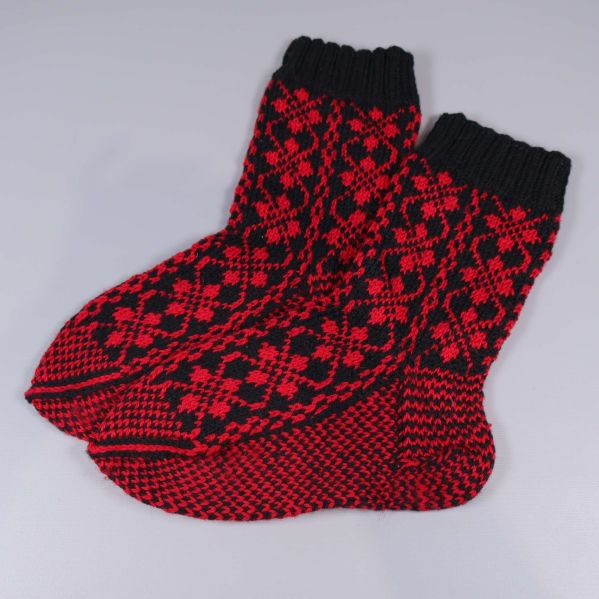 Ett par stickade röd- och svartmönstrade strumpor sida vid sida