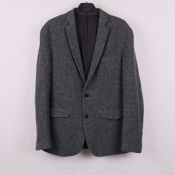 Mörkgrå kavaj upphängd på galge sedd framifrån