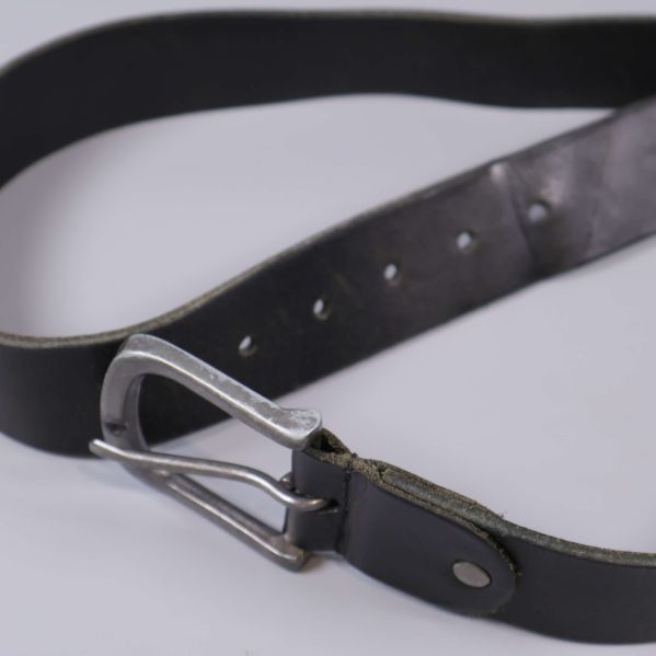 Svart läderbälte upplagt i cirkel med metallspänne