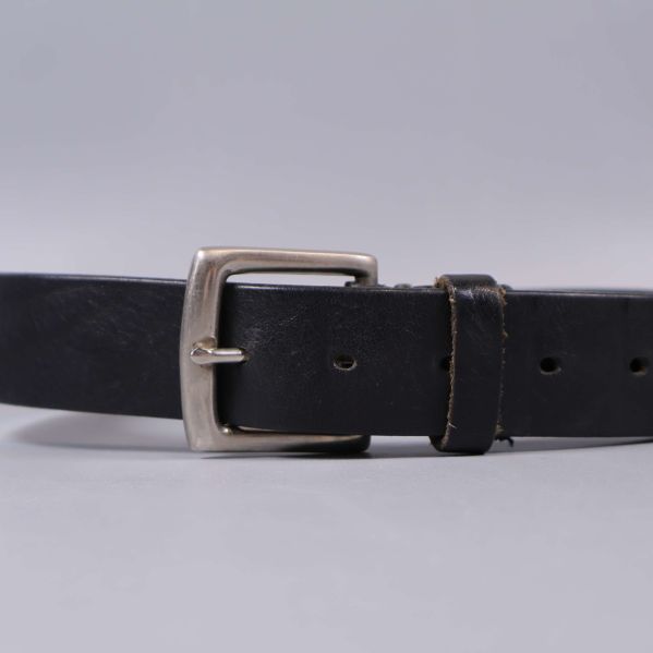 Närbild på bältesspänne och läderrem i svart