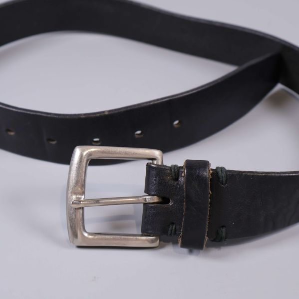 Svart bälte liggande med synligt spänne och flertalet hål