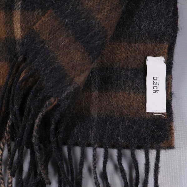 Fransad ände av rutigt halsdukstyg med etiketten black