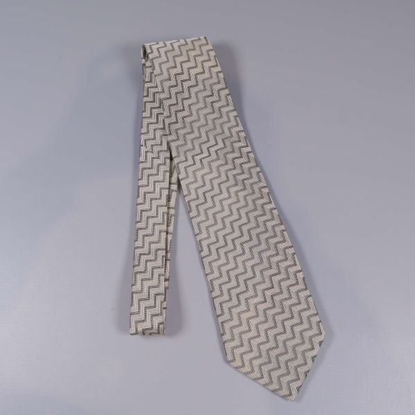 Slips i beige nyans liggande på grå bakgrund