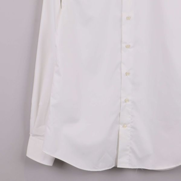 Närbild på nederkant och ärmslut av vit skjorta