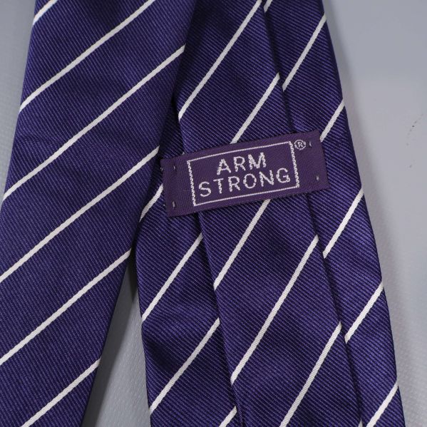 Närbild på Armstrong-märke på blå slips