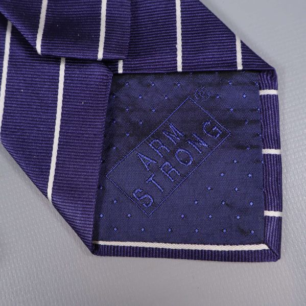 Närbild på broderad Armstrong-logga på slipsens baksida