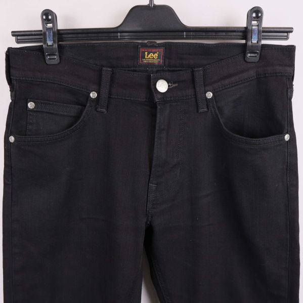 Närbild på framfickor, knapp och dragkedja på svarta jeans