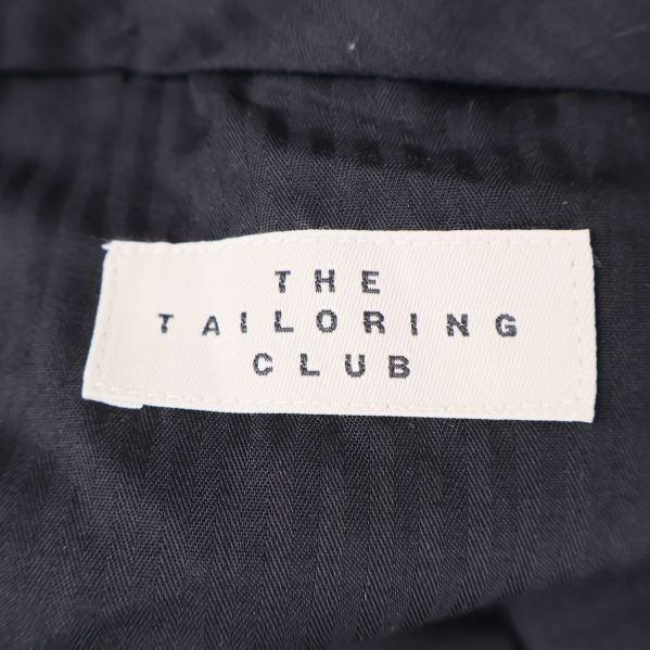 Vit etikett med text The Tailoring Club