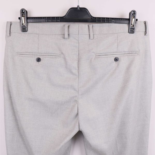 Närbild av dubbla bakfickor på ljusgrå kostymbyxa