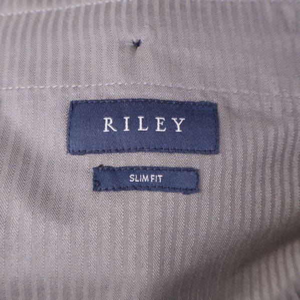 Närbild av blå etikett med RILEY och slim fit-tygskylt