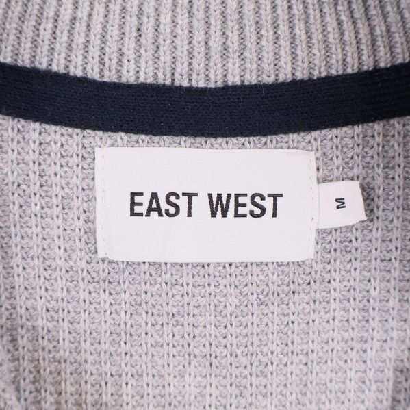 Närbild på etikett med EAST WEST och storlek M