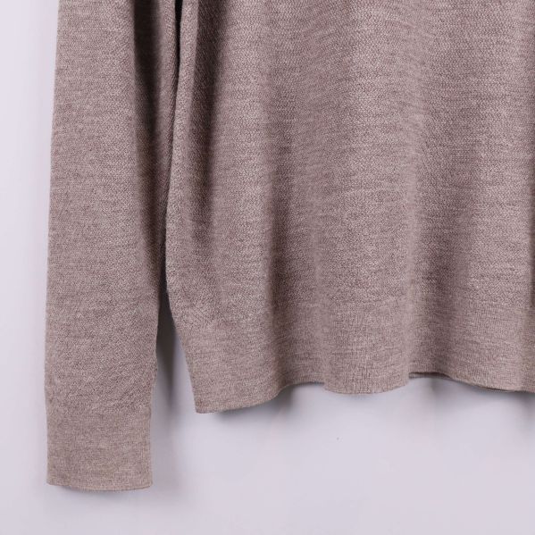 Nedre del av beige tröja med rak nederkant och lång ärm