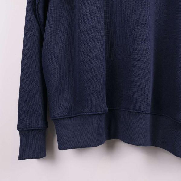 Närbild på vänster nederkant och muddar av blå tröja