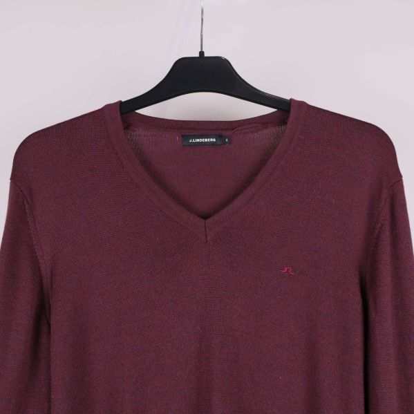 Närbild på v-ringning och logga framtill på tröjan