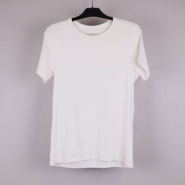 Vit t-shirt på galge framifrån mot ljus bakgrund