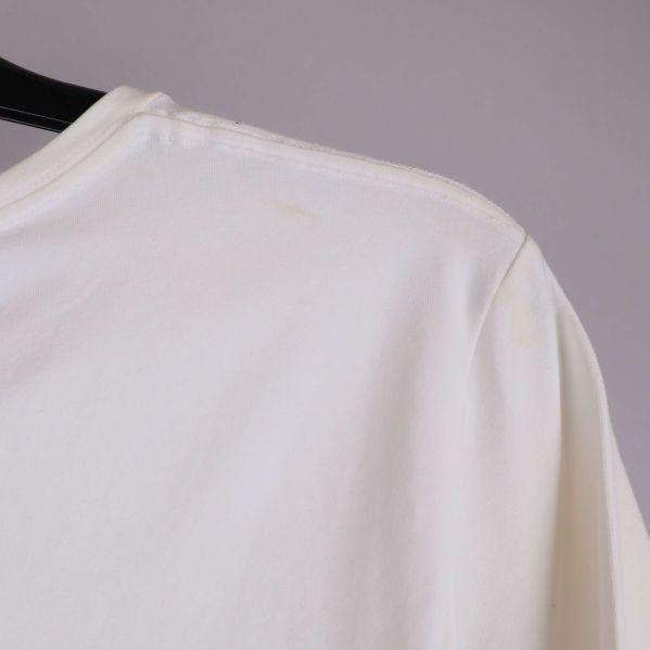 Närbild på höger axel med synlig fläck på vit t-shirt