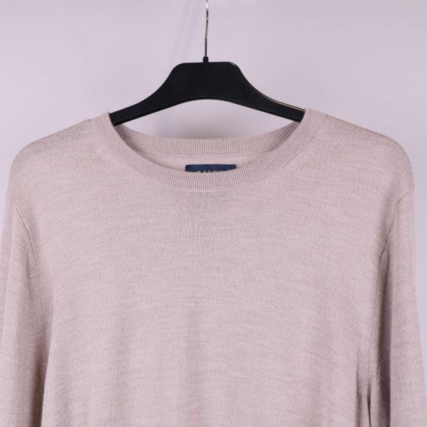 Närbild av halsringning och axel på beige tröja