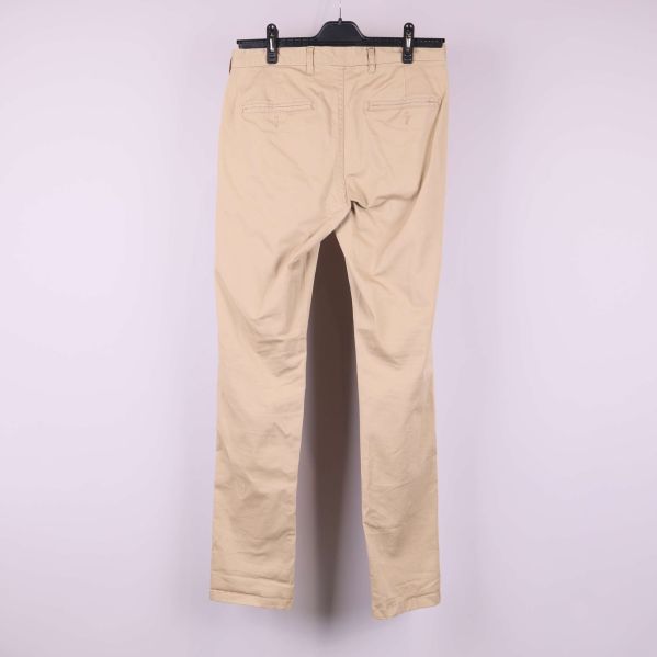 Baksida av beiga byxor med fickor på galge