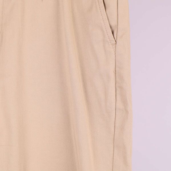 Närbild på sidosöm och ficka på beiga byxor