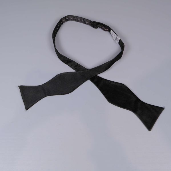 Svart självknutande fluga utlagd på ljus yta