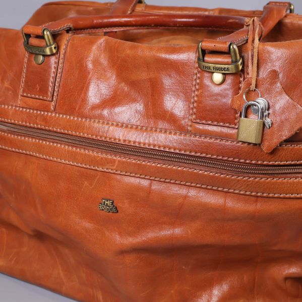 Närbild på läderväska med dragkedja och lås, detaljer i metall