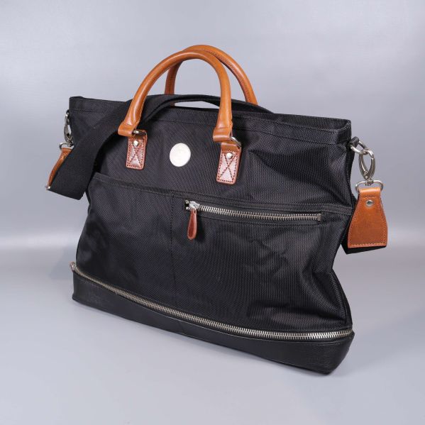 Svart weekendbag med bruna handtag och axelrem