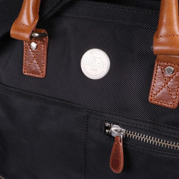 Närbild på väska med metallogo, blixtlås och läderdetaljer