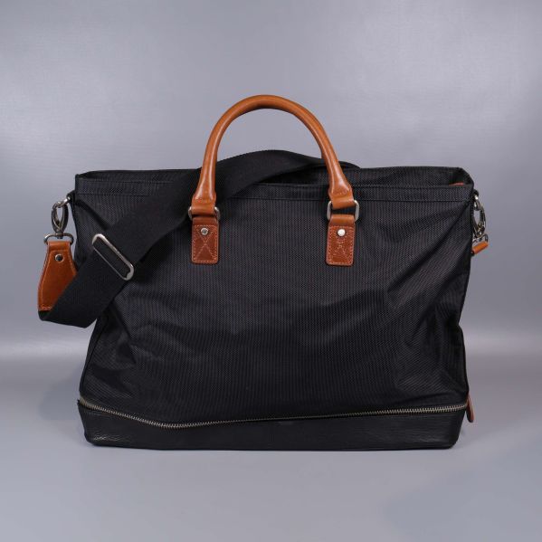 Baksidan av svart weekendbag med läderhandtag och axelrem