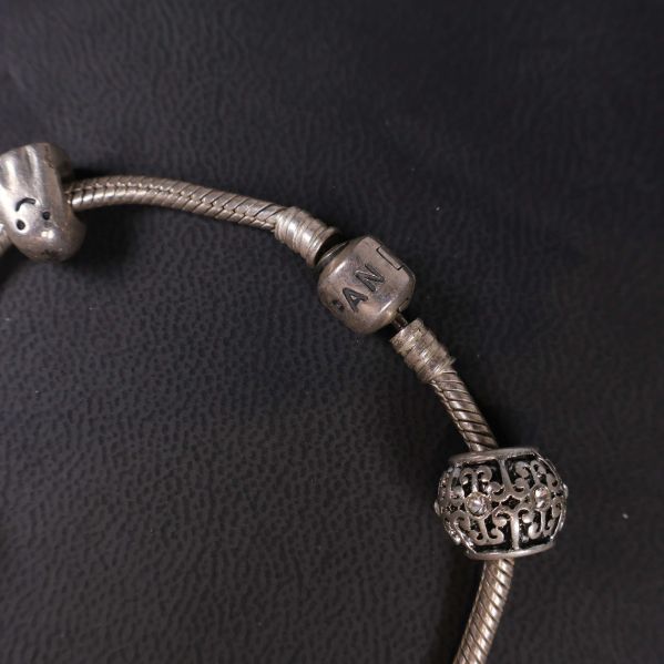 Detaljbild av PAN-märkt berlock och mönstrad pärla