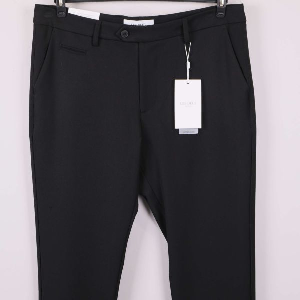 Framdel av svarta kostymbyxor med fickor och etikett